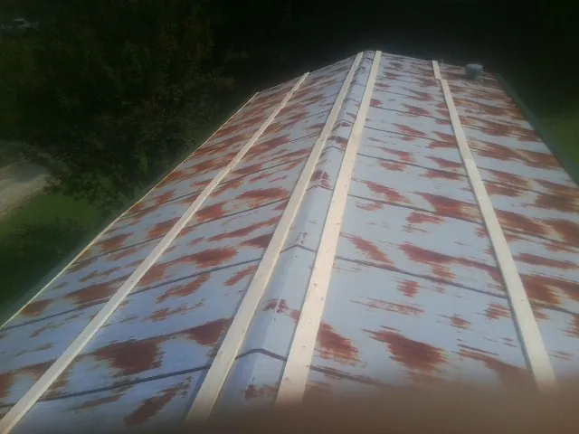 Rusted metal roof panels with new wood purlins before replacement — Storm Damage Roof Repair in Olsburg by Roofing Brothers