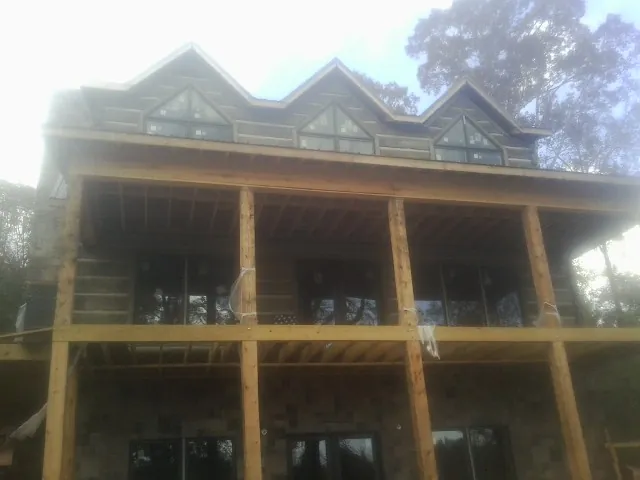 Dormers and porch framing on a large log home under construction — Roof Coating work by our crew in Olsburg