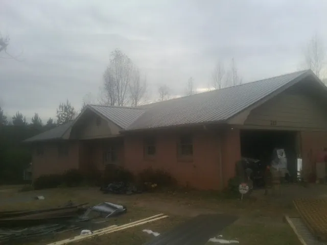 Gray metal roof on a stucco house with an attached garage in Olsburg
