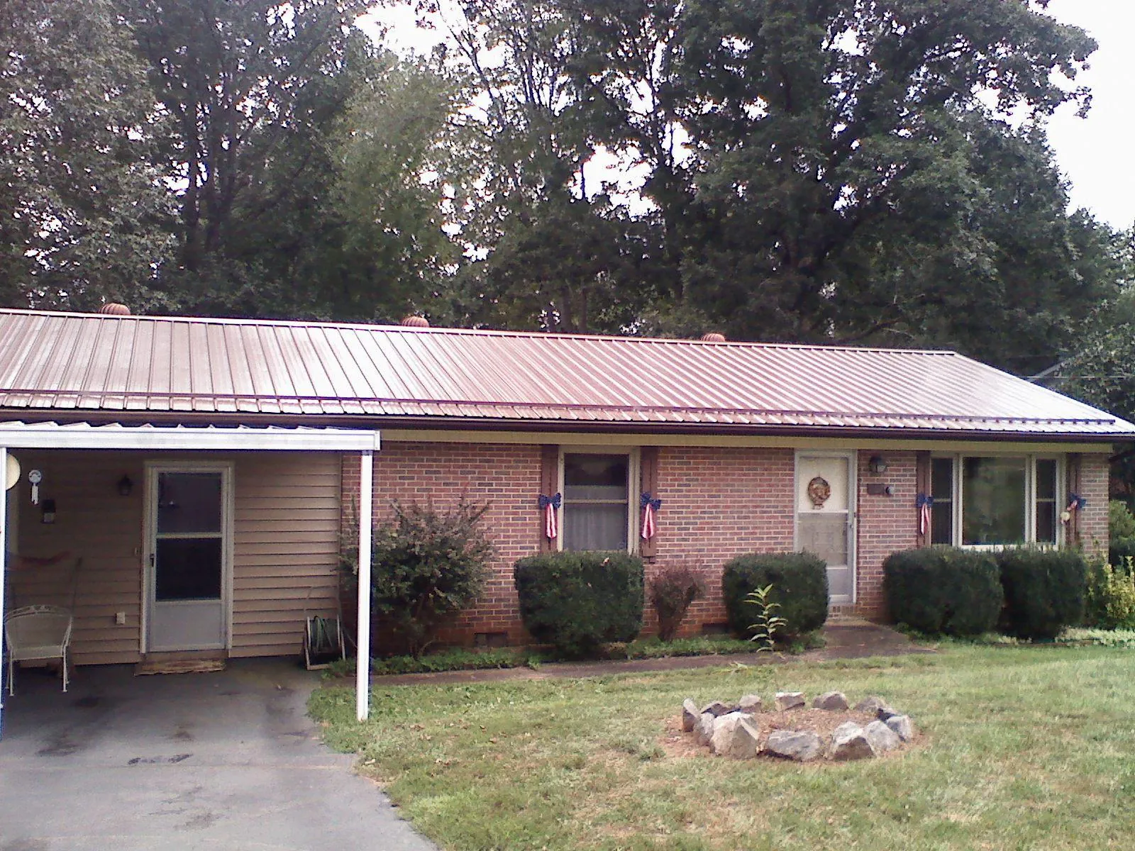 Bronze metal roof and carport on a brick ranch home — Roof Repair work by our crew in Olsburg